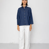 Person wearing a blue shirt and white pants against a white background