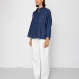 Person wearing a blue shirt and white pants against a white background