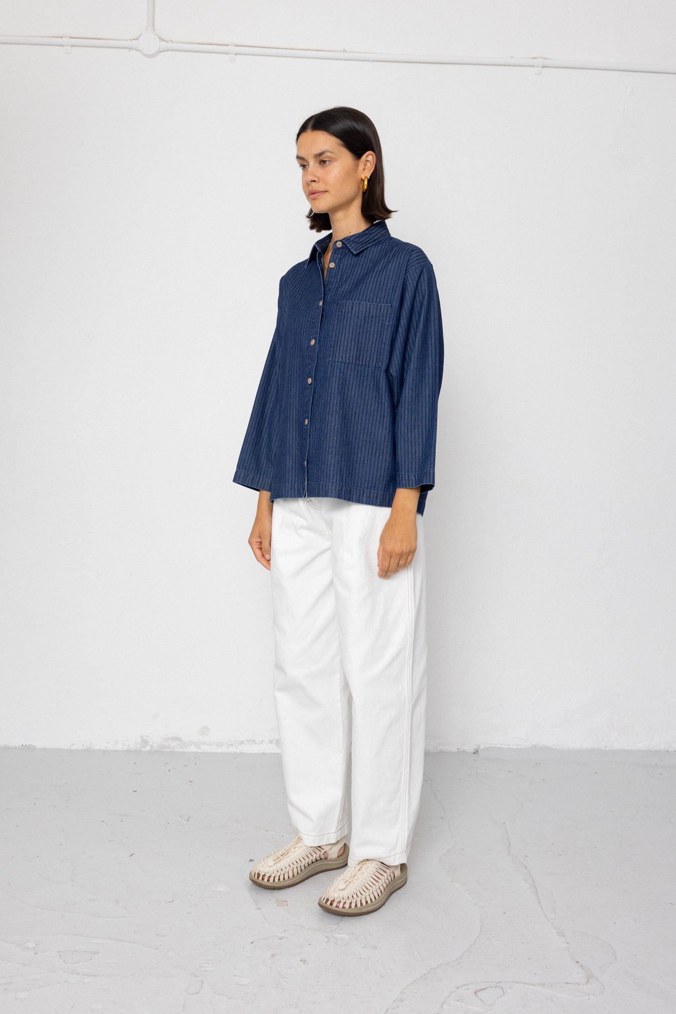 Person wearing a blue shirt and white pants against a white background