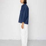 Person wearing a blue shirt and white pants against a white background