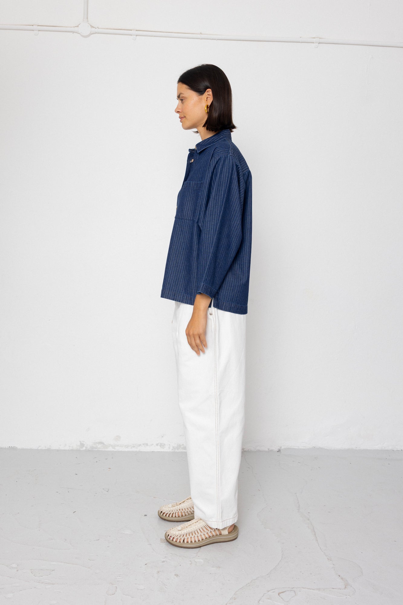Person wearing a blue shirt and white pants against a white background