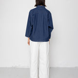 Person wearing a blue striped shirt and white pants against a white background