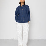 Person wearing a blue shirt and white pants against a white background