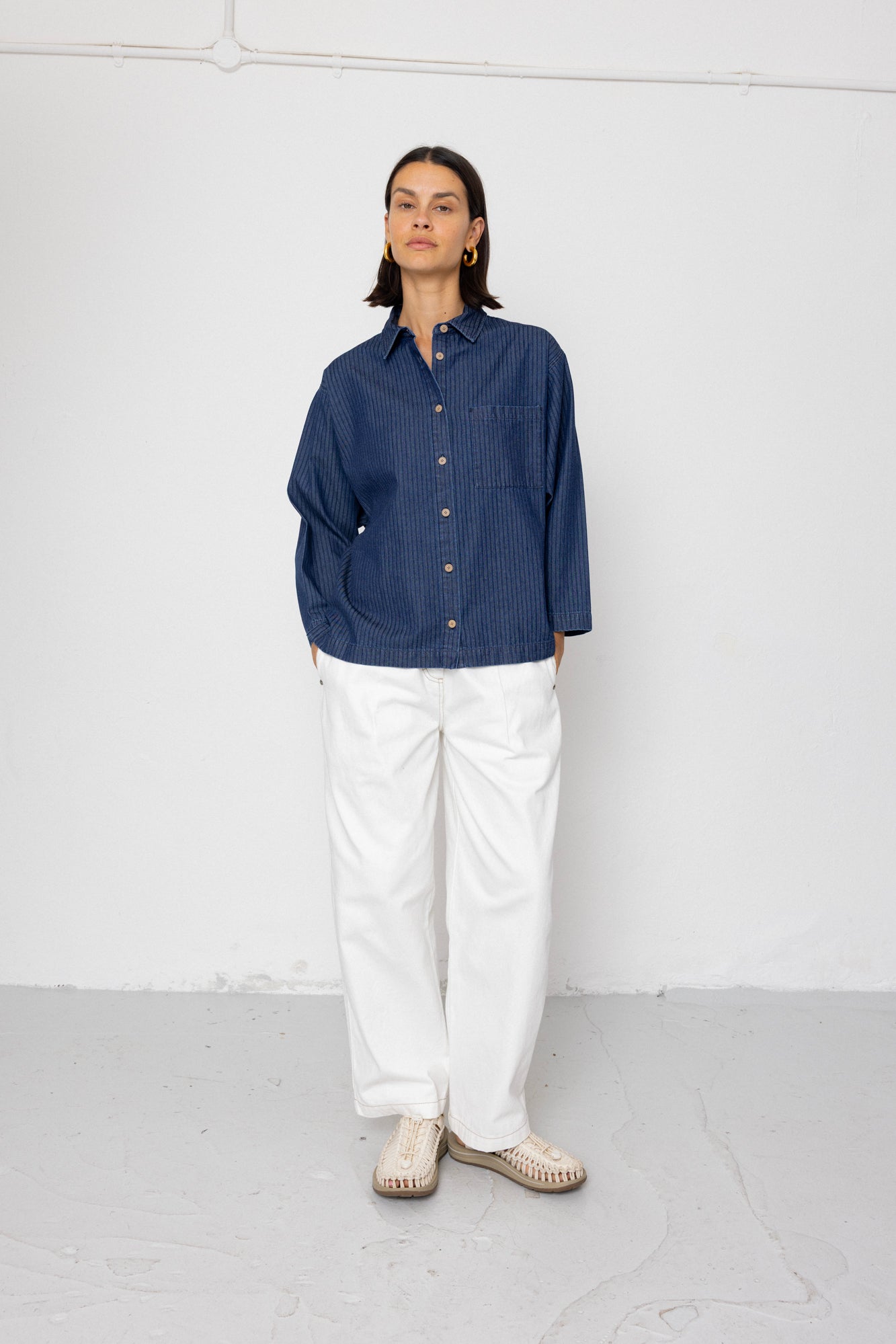 Person wearing a blue shirt and white pants against a white background
