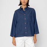 Woman wearing a blue striped shirt and white pants on a white background