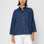 Woman wearing a blue striped shirt and white pants on a white background