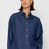 Woman wearing a blue striped shirt against a white background