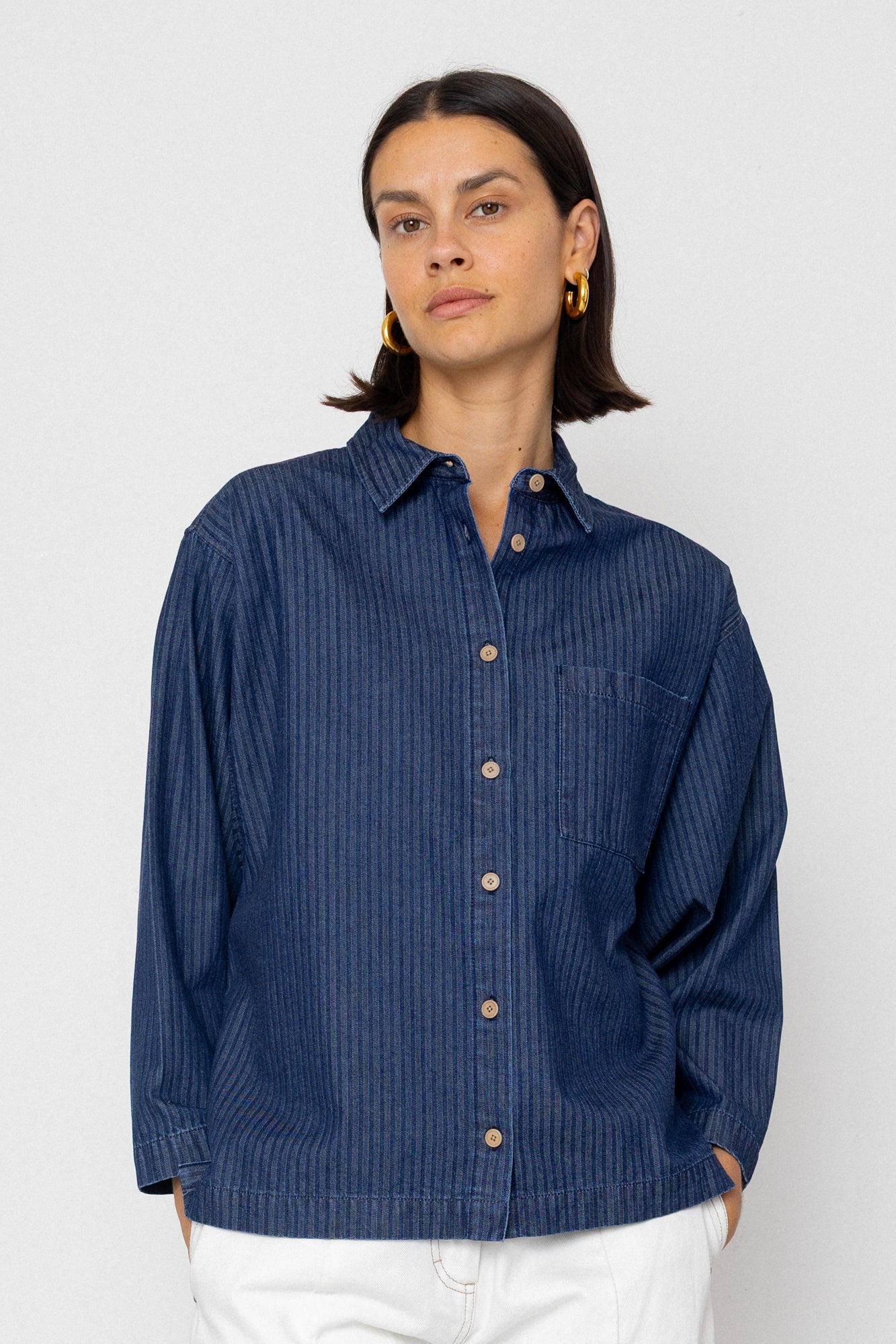 Woman wearing a blue striped shirt against a white background
