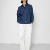 Person wearing a blue shirt and white pants against a white background