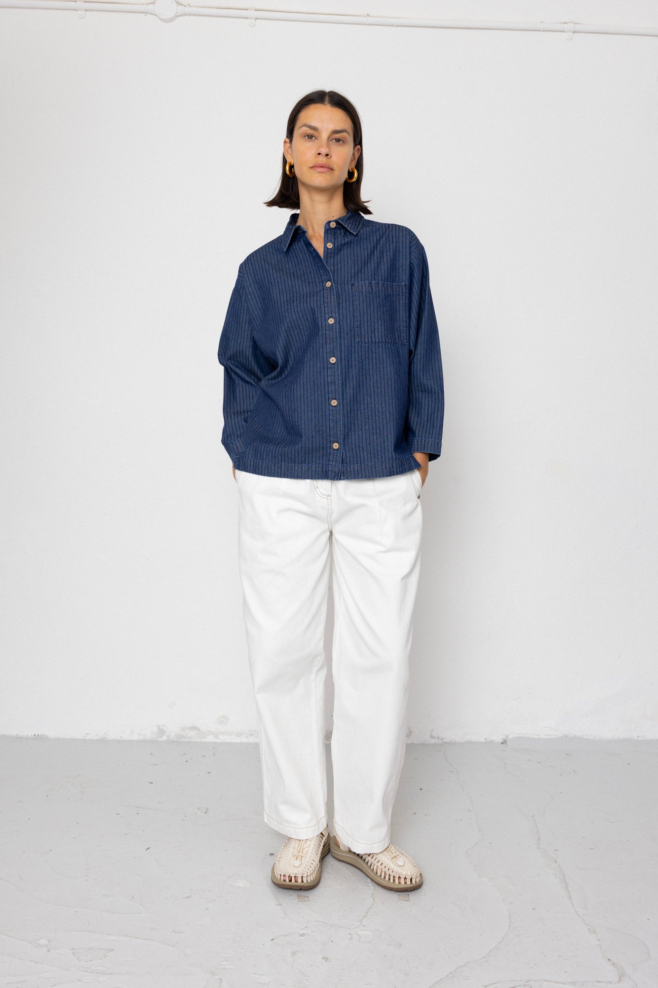 Person wearing a blue shirt and white pants against a white background