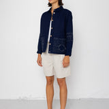 Woman wearing a navy jacket and white shorts against a white background