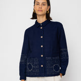 Person wearing a dark blue jacket with patterned patches on a white background