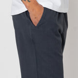 Person wearing dark gray pants and a white shirt on a plain background