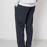 Person wearing a light gray sweatshirt, dark pants, and gray sneakers against a white background
