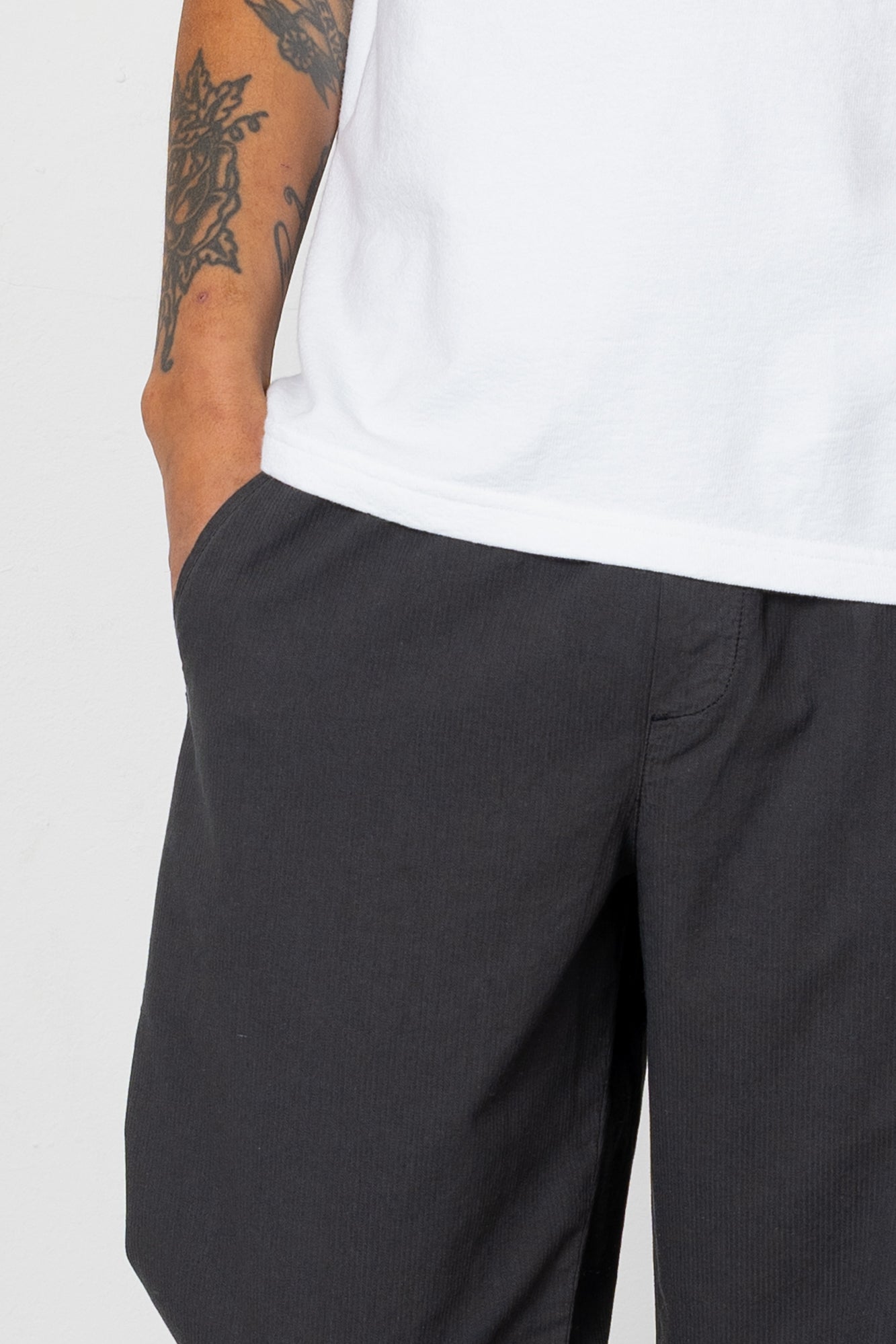 Person wearing black pants and a white shirt on a plain background