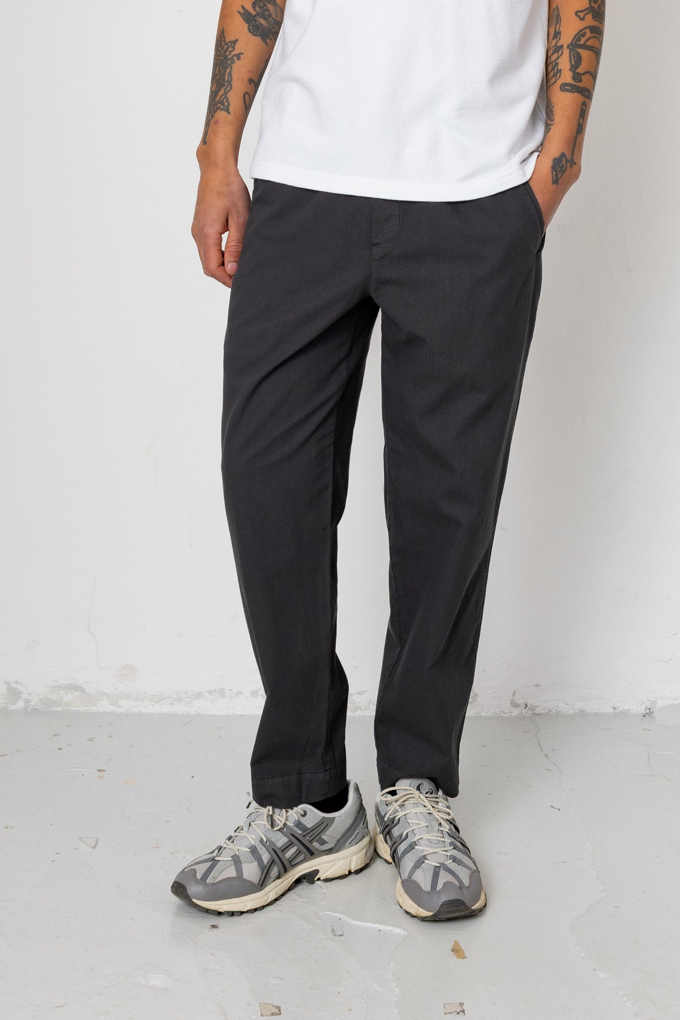 Person wearing black pants and gray sneakers on a white background