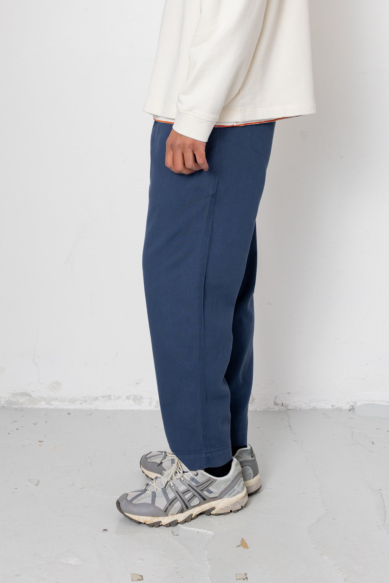 Person wearing blue pants and gray sneakers on a white background