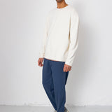 Man wearing a white sweater and blue pants against a white background