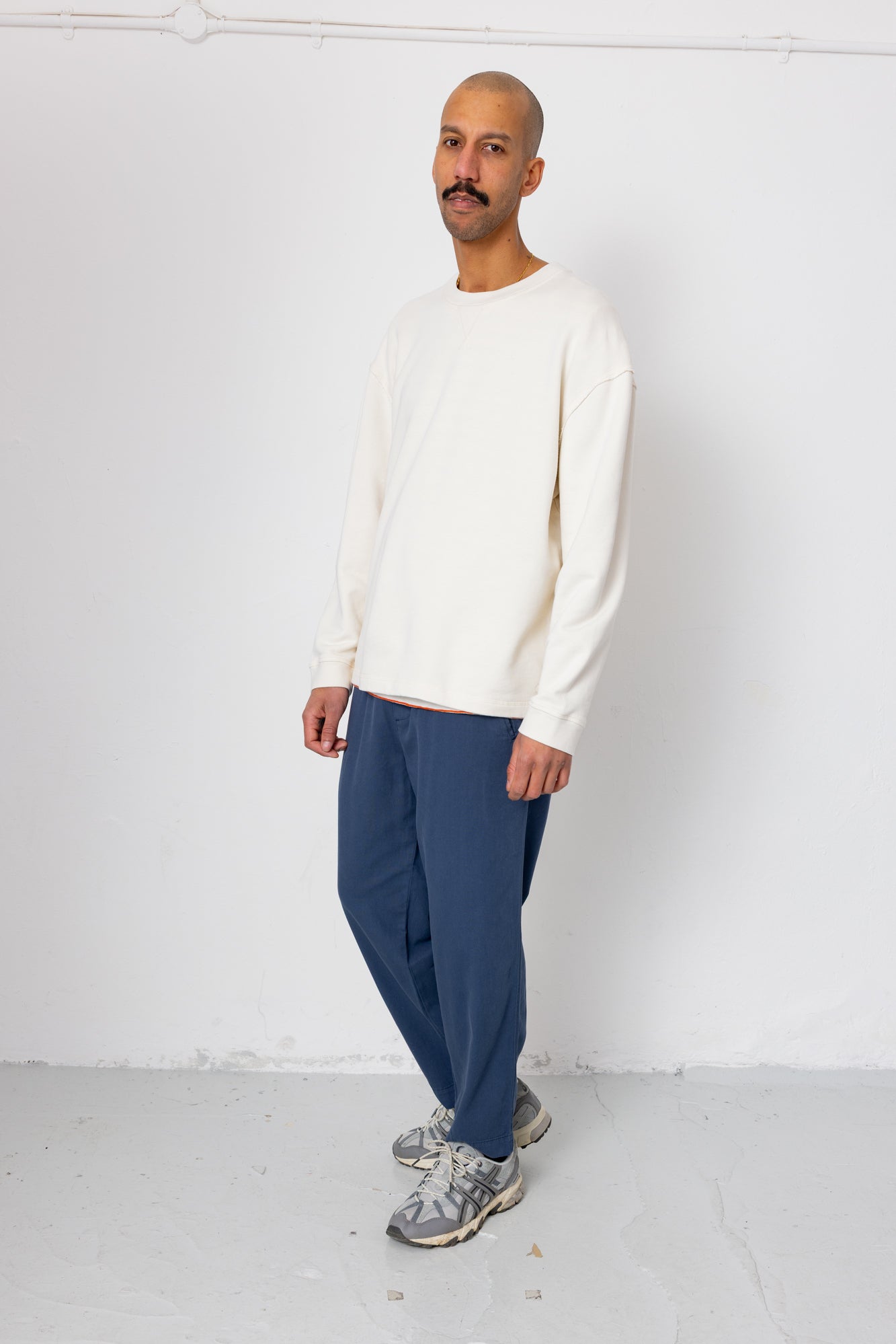 Man wearing a white sweater and blue pants against a white background