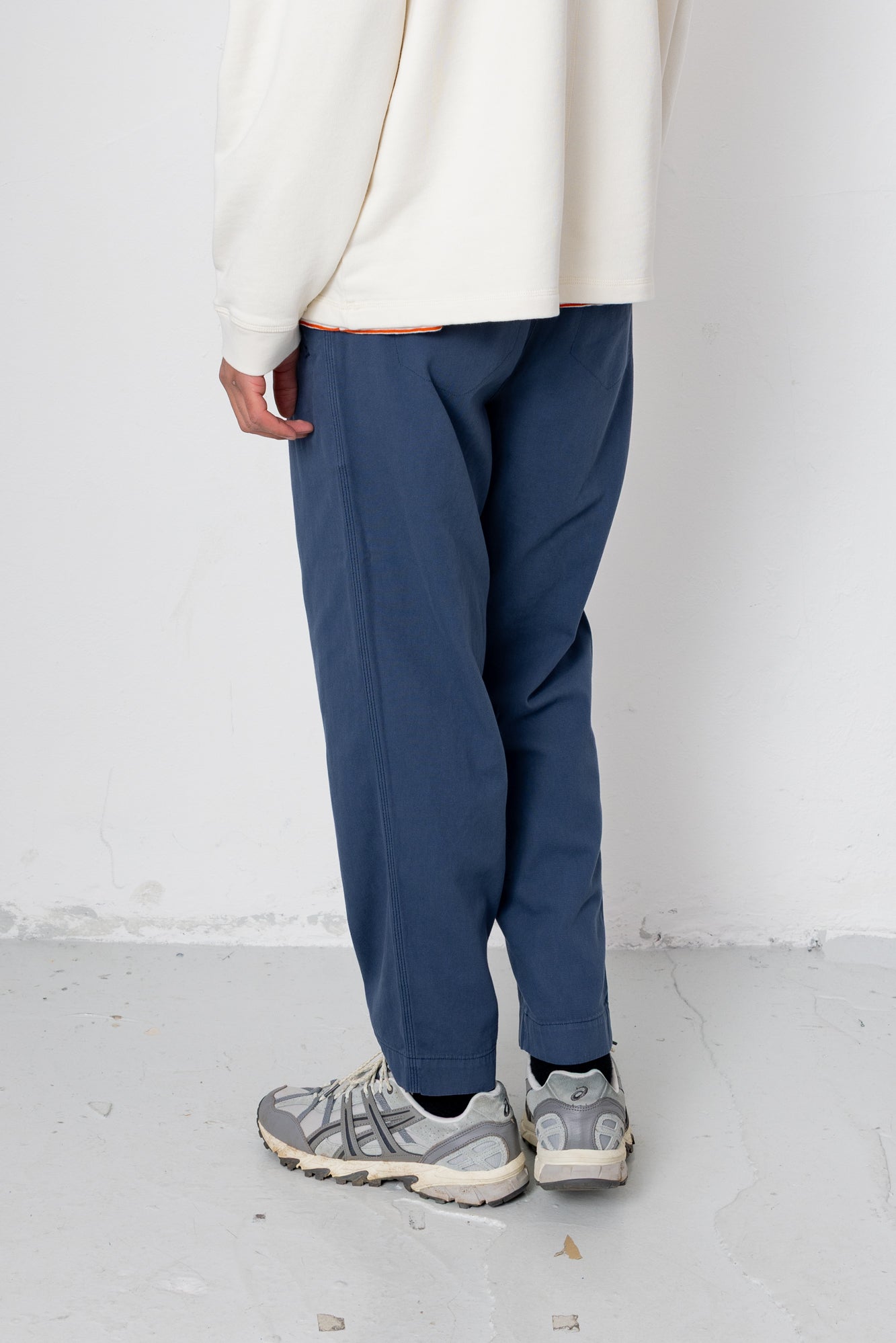 Person wearing blue pants and a white top on a white background
