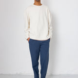 Man wearing a white sweater and blue pants against a white background