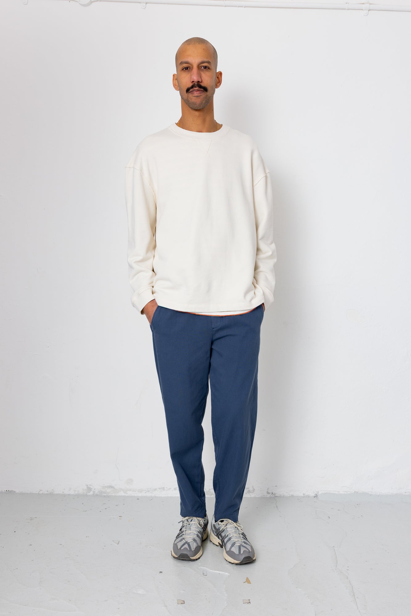Man wearing a white sweater and blue pants against a white background