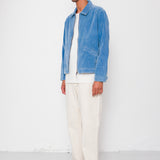 Man wearing a blue jacket, white shirt, and white pants against a white background
