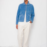 Man wearing a blue jacket and white pants against a white background