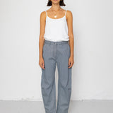 Person wearing a white tank top and striped denim trousers against a white background