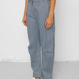 Person wearing denim striped pants and white shoes on a plain background