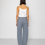 Woman wearing a white top and striped blue pants against a white background