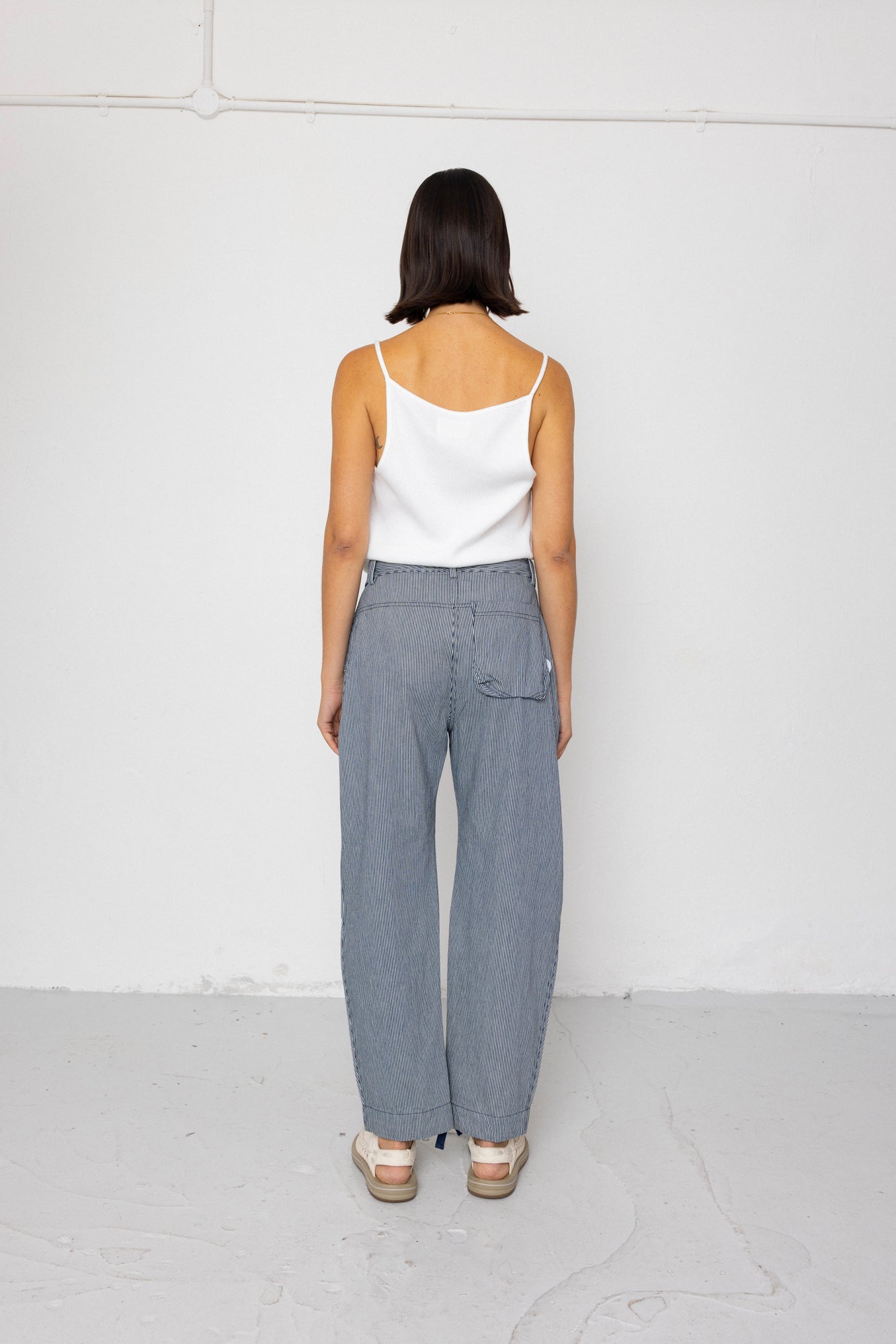 Woman wearing a white top and striped blue pants against a white background