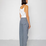Person wearing a white top and striped denim pants against a white background