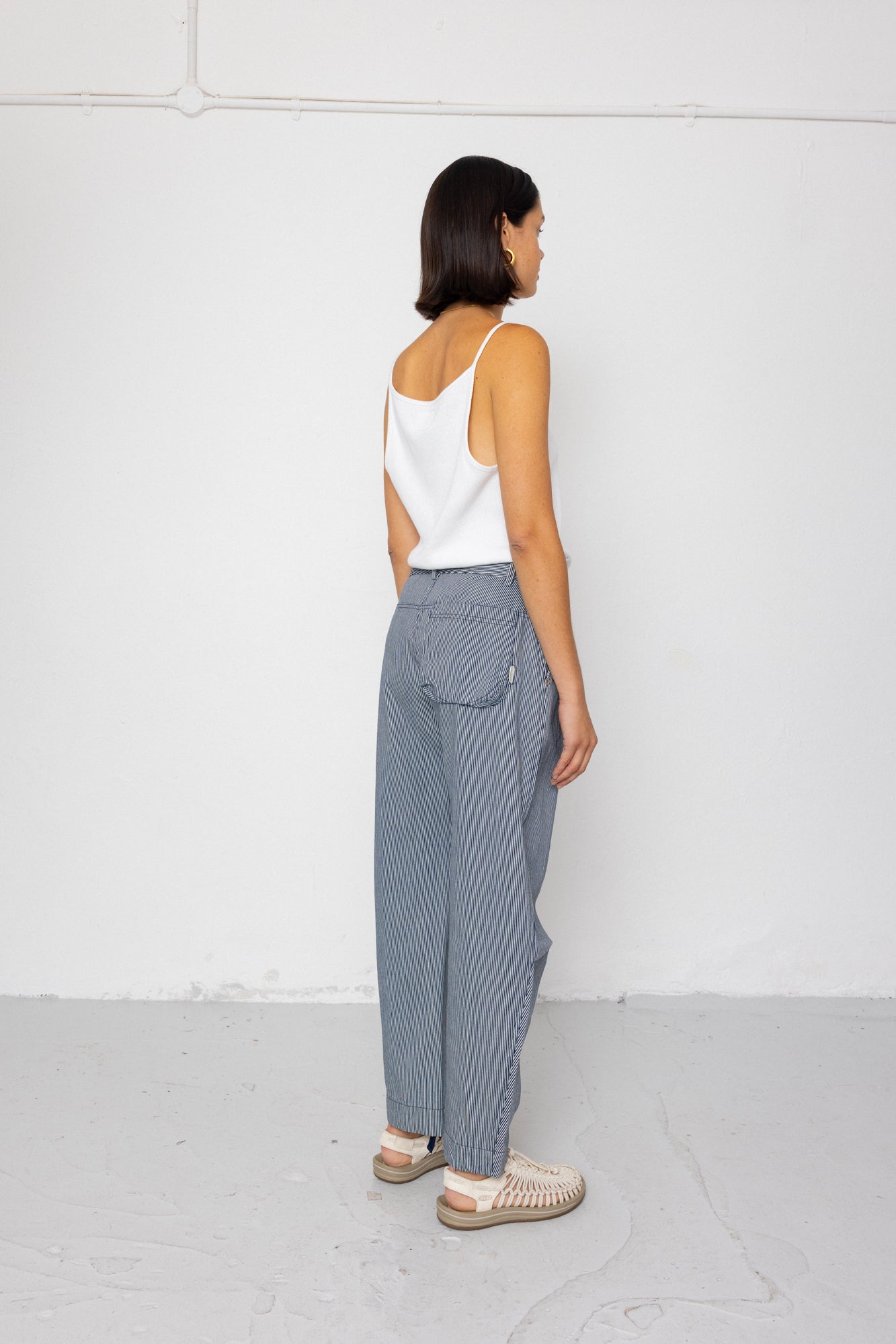 Person wearing a white top and striped denim pants against a white background