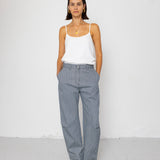 Woman wearing a white tank top and striped denim pants against a white background