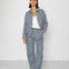 Person wearing a striped blue denim outfit with a white background