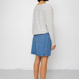 Person wearing a striped shirt and denim skirt against a white background