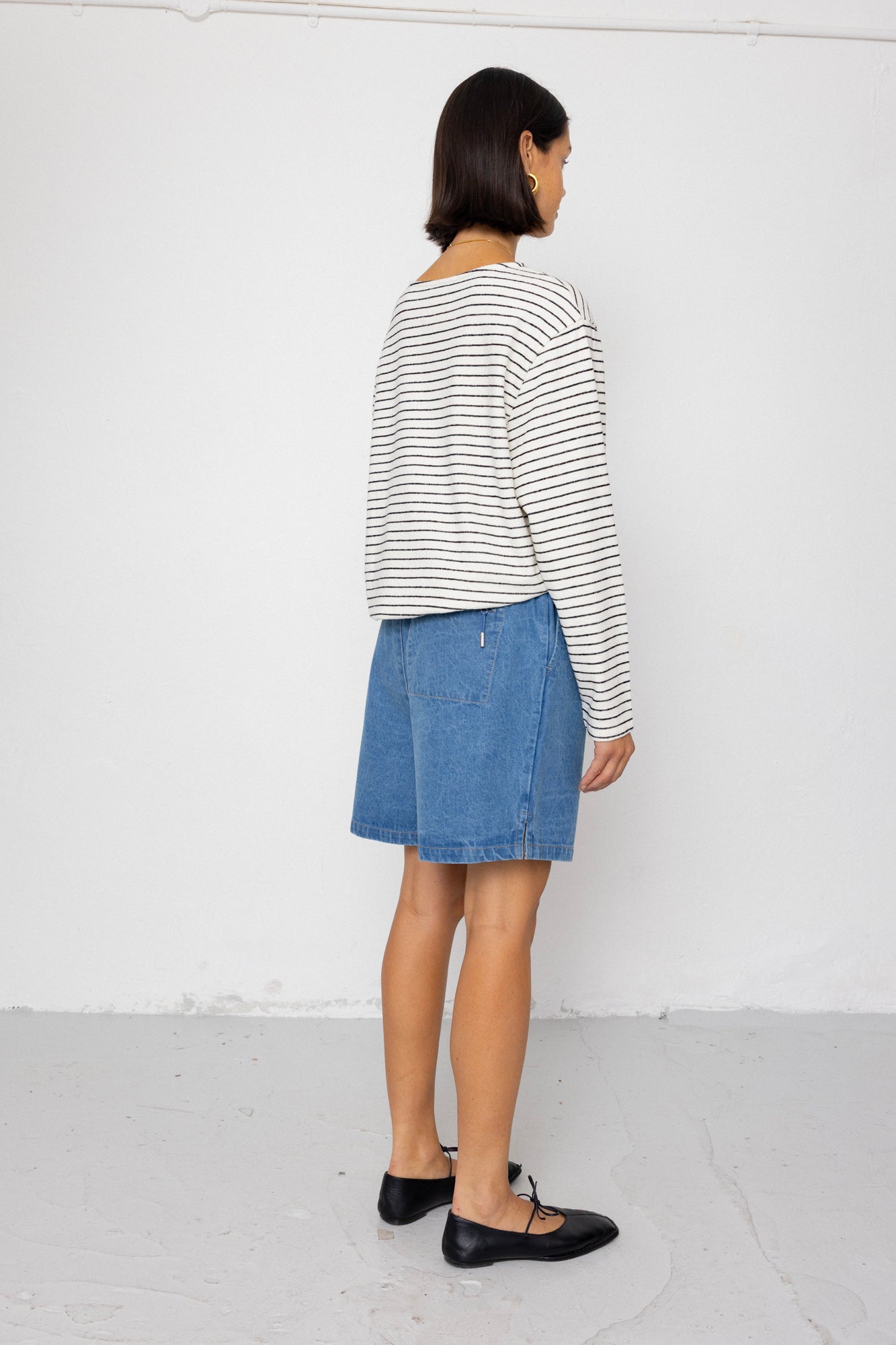 Person wearing a striped shirt and denim skirt against a white background