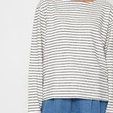 Person wearing a black and white striped long-sleeve top with blue shorts on a white background