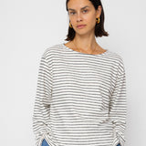 Woman wearing a striped shirt and blue jeans against a white background