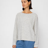 Person wearing a black and white striped long-sleeve top with blue shorts on a white background