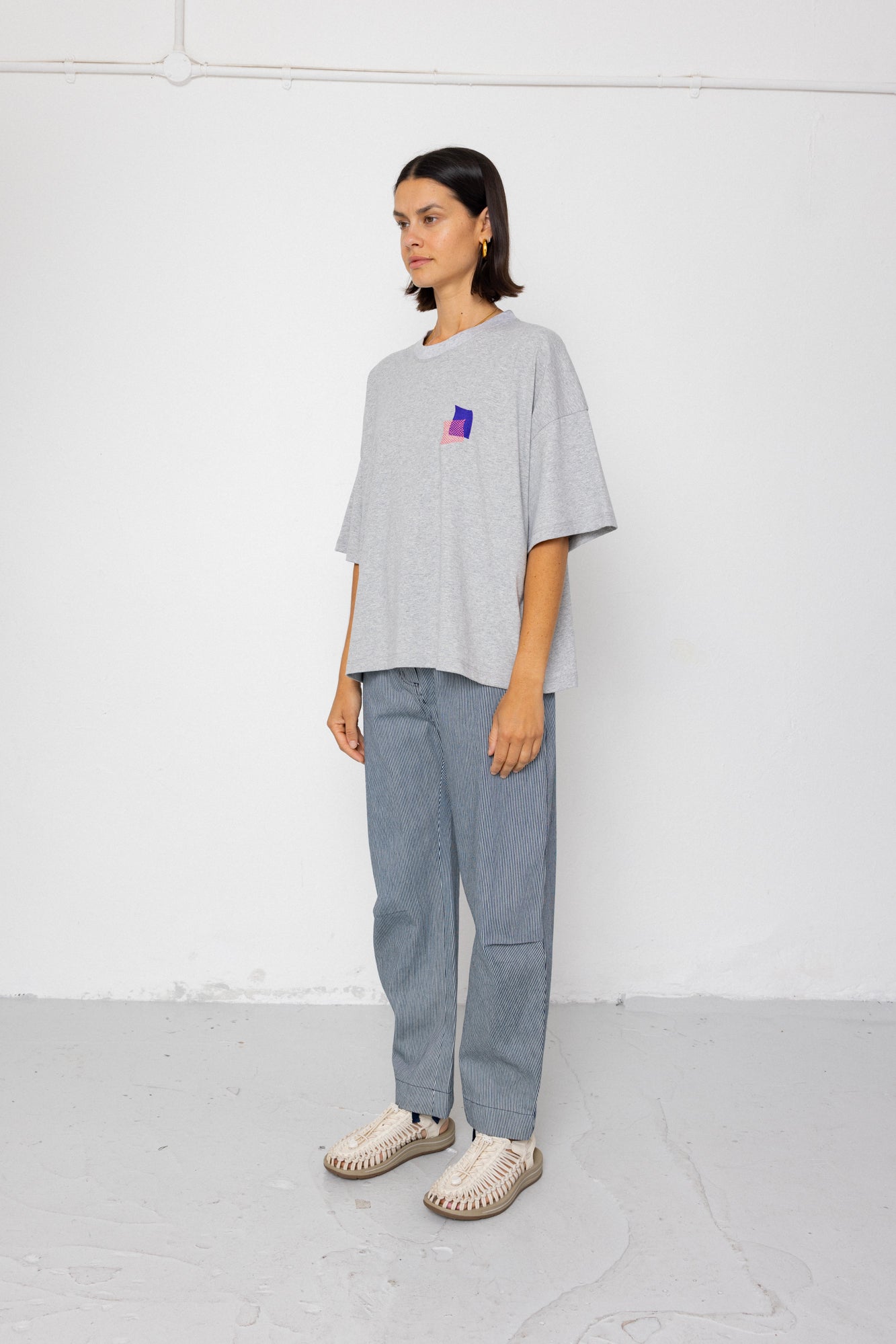 Person wearing a light gray oversized t-shirt and pants on a white background