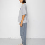 Person wearing a gray oversized t-shirt and light blue pants against a white background