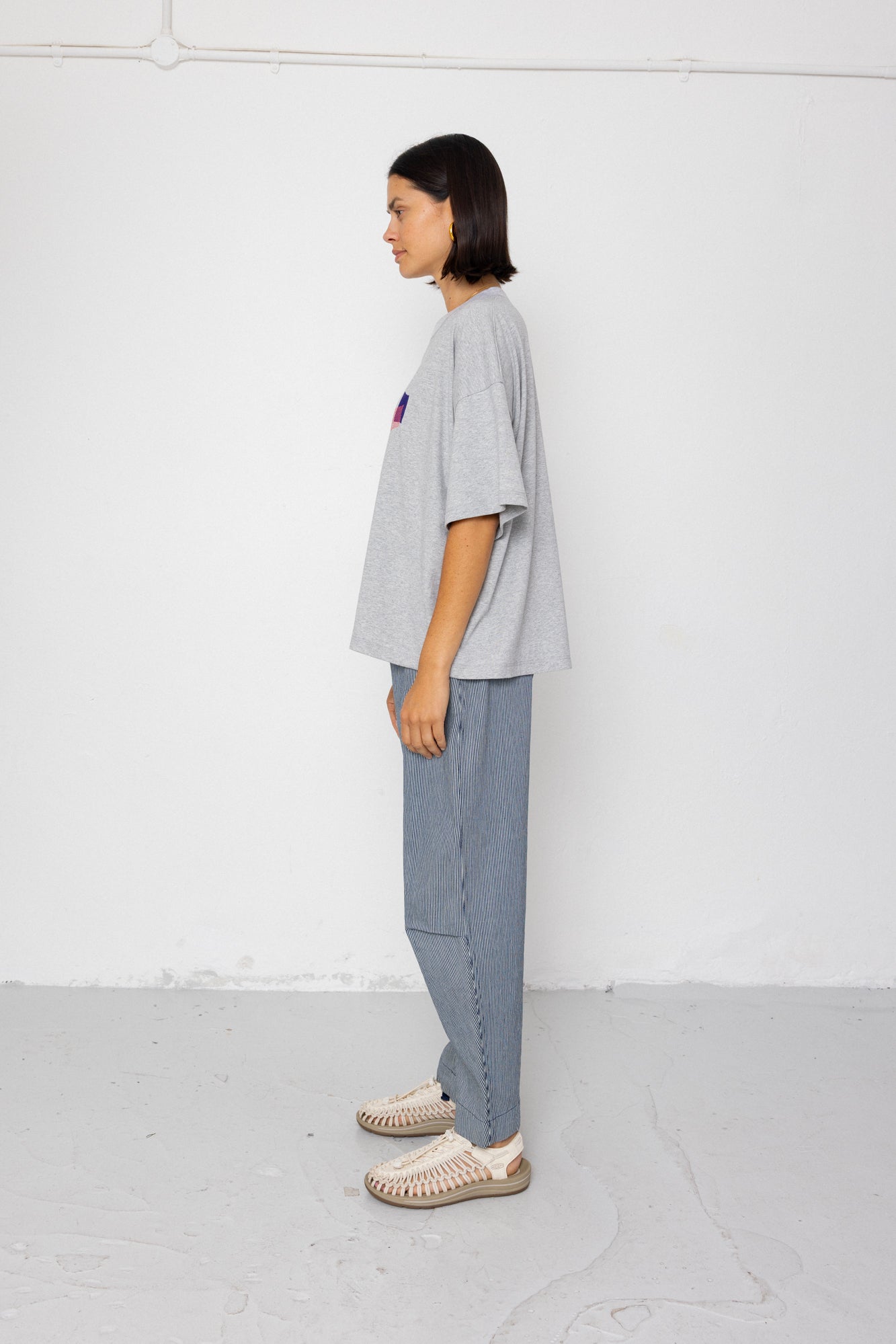 Person wearing a gray oversized t-shirt and light blue pants against a white background