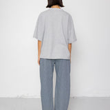 Person wearing a light gray t-shirt and blue pants against a white background