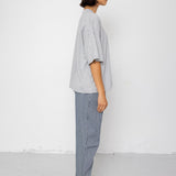 Person wearing a light gray oversized shirt and pants standing against a white background