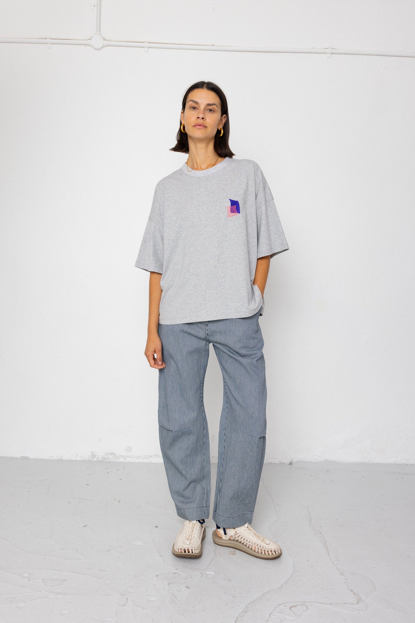 Person wearing a gray oversized t-shirt and pants on a white background
