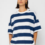 Person wearing a navy and white striped shirt with white pants on a light gray background