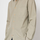 Beige button-up shirt worn by a person on a white background