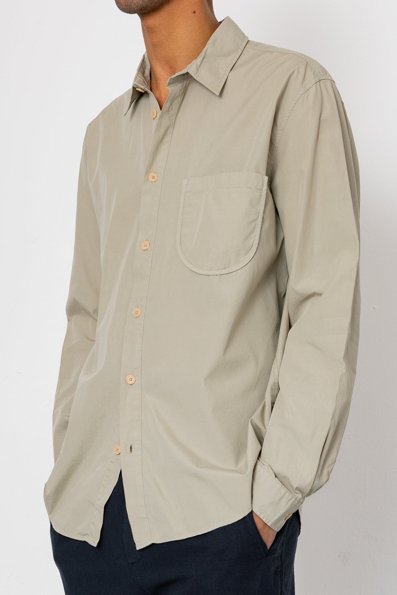 Beige button-up shirt worn by a person on a white background